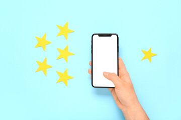 Woman with blank mobile phone and rating stars on blue background. Customer experience concept