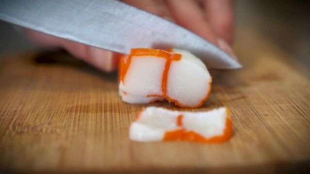 Slicing surimi on a bamboo chopping board