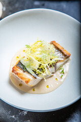 Pescado fresco con salsa con hierbas decorativas servido en un plato y decorado en una mesa de restaurante delicioso y muy jugoso