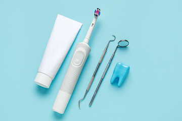 Electric toothbrush, tooth model and dental tools on blue background. World Dentist Day