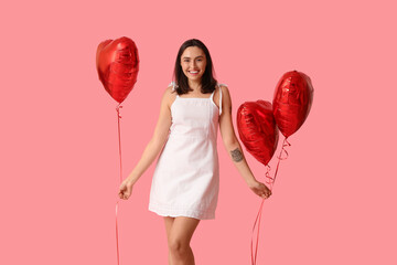 Beautiful young woman with air balloons in shape of heart on pink background. Valentine's Day...