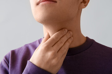 Young man with thyroid gland problem on light background, closeup