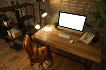 Blank computer monitor with telephone on table in office at night