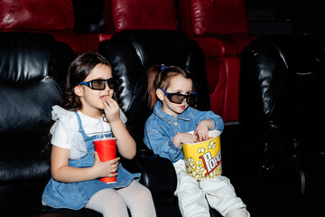 Little girls, friends or sisters in 3d glasses watching a cartoon film at a movie theater, house or...