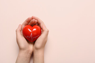 Female hands with red heart on pink background