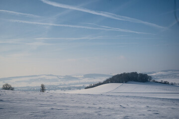 Fototapeta na wymiar Winter landscape with snow covered hills and blue sky. Beautiful winter background.