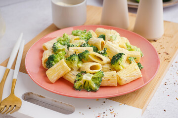 Plate of tasty pasta with broccoli on white background