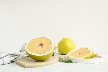 Board and plate with cut fresh pomelo fruit on white background