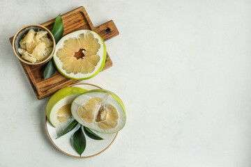 Wooden board and plate with cut fresh pomelo fruits on white background