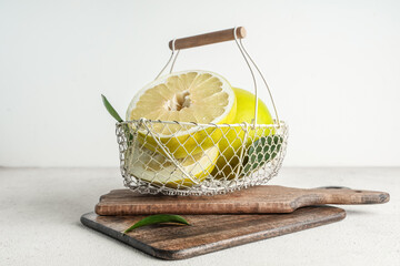 Basket with fresh pomelo fruits and leaves on white background