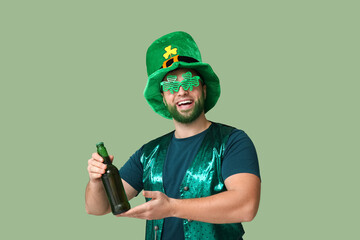Young man in leprechaun hat and decorative glasses in shape of clover  with green beard holding...