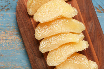 Board with fresh pomelo fruit on blue wooden background