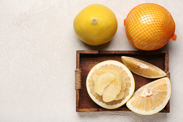 Wooden tray with cut fresh pomelo fruit on white background
