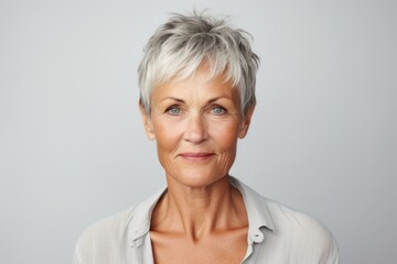 Fototapeta premium Portrait of a senior woman with grey hair against a grey background.