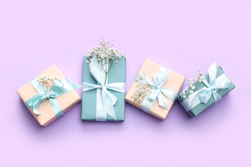 Gift boxes with beautiful gypsophila flowers on lilac background. International Women's Day