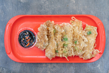 Fried tempeh or tempe goreng, a traditional Indonesian food made from fermented soybean. Served sambal (chili paste) on a red plate. 