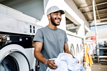 African American man with a cap happily engaged in laundry day at a laundromat. Energy saving at home, eco-friendly and sustainability concept