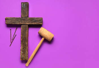 Wooden cross with hammer and nails on purple background. Good Friday concept