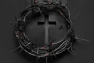 Cut black paper in shape of cross with crown of thorns on dark background. Good Friday concept