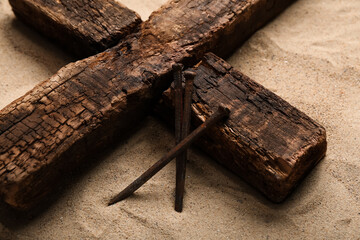 Wooden cross with nails on sand. Good Friday concept