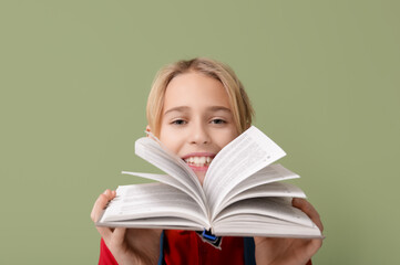 Cute little boy with book on green background