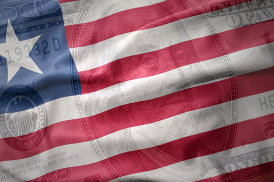waving colorful flag of liberia on a american dollar money background. finance concept.