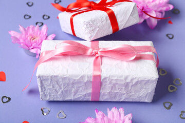 Gift boxes with beautiful chrysanthemum flowers and confetti on purple background. Valentine's Day celebration