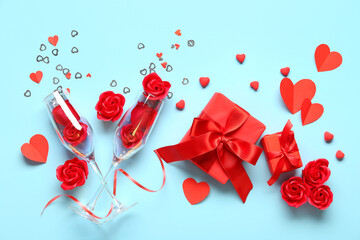 Fototapeta na wymiar Gift boxes with red roses, champagne glasses and paper hearts on blue background. Valentine's Day celebration