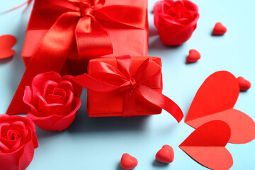 Gift boxes with red roses and paper hearts on blue background. Valentine's Day celebration