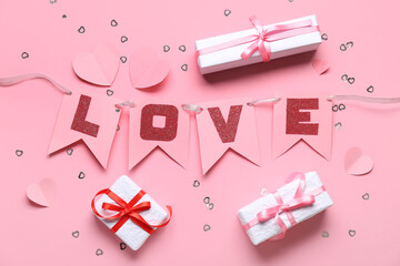 Garland made of paper flags with word LOVE and gift boxes on pink background. Valentine's Day celebration