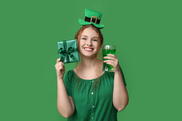 Young redhead woman with beer and gift on green background. St. Patrick's Day celebration