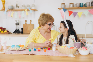 Happy easter! A grandmother and her granddaughter painting Easter eggs