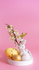 White rabbit, blossom twig and Easter eggs on a pink background. Easter minimalistic composition
