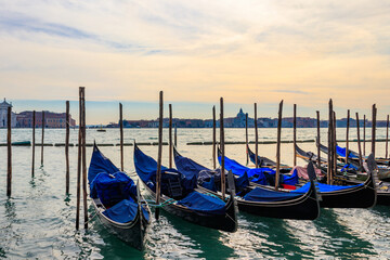 Fototapeta na wymiar Traditional Gondolas moored on the pier in the Grand Canal in Venice, Italy