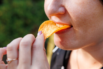 Chewing mouth while eating, woman eats classic chips. Background with selective focus and copy space