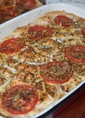 Close up of italian Focaccia bread with tomato slices, onion strips and spices