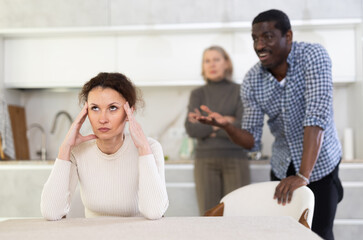 Upset woman not talking after disagreement with husband and mother standing behind