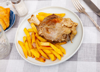 Appetizing braised pork knuckle served with garnish of crispy french fries