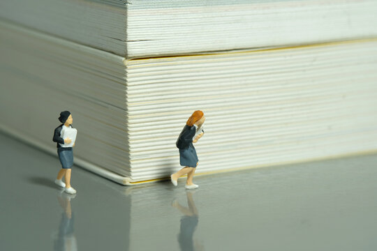 Miniature people toy figure photography. Two girl pupil students running on a book corridor