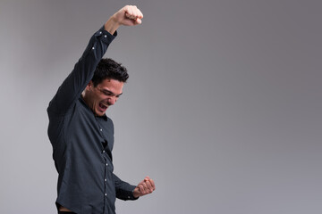 Young man celebrates, arms up, masculine