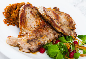 Delicious roasted pork shin served with stewed lentils, fresh greens and red currant berries