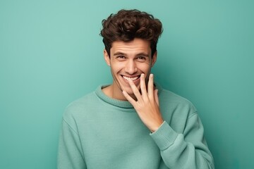 handsome man smiling covering his mouth - obrazy, fototapety, plakaty