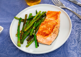 Fresh salmon steak with bunch of roasted asparagus on table.