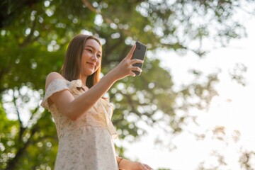 Naklejka premium Young woman using phone in a public park