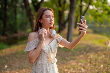 Young beautiful woman with headphone enjoying music and personal moment in a nature park