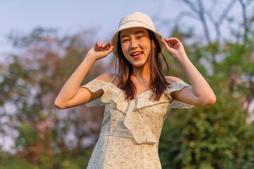 Beautiful young asian woman enjoying nature and sunset breeze at a park