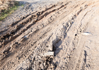 Muddy road, frozen mud, frost on the grass and sheets of ice in puddles. Pre-winter in Poland.