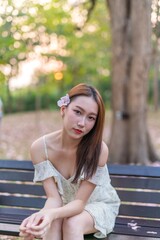 Beautiful young asian woman enjoying outdoor breeze during sunset moments at a public park with lots of sakura flowers