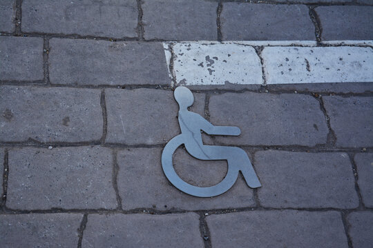 Emplacement de stationnement pour les handicapés marqué pour un symbole en relief découpé dans du métal.