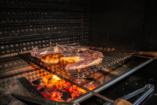 Churrasco brasileiro com grellha assando picanha e p&atilde;o de alho ainda espeto com cora&ccedil;&atilde;o de frango.